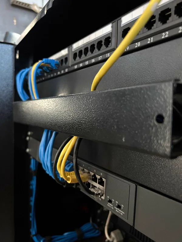 Detalhe de patch panel e switch com cabeamento organizado